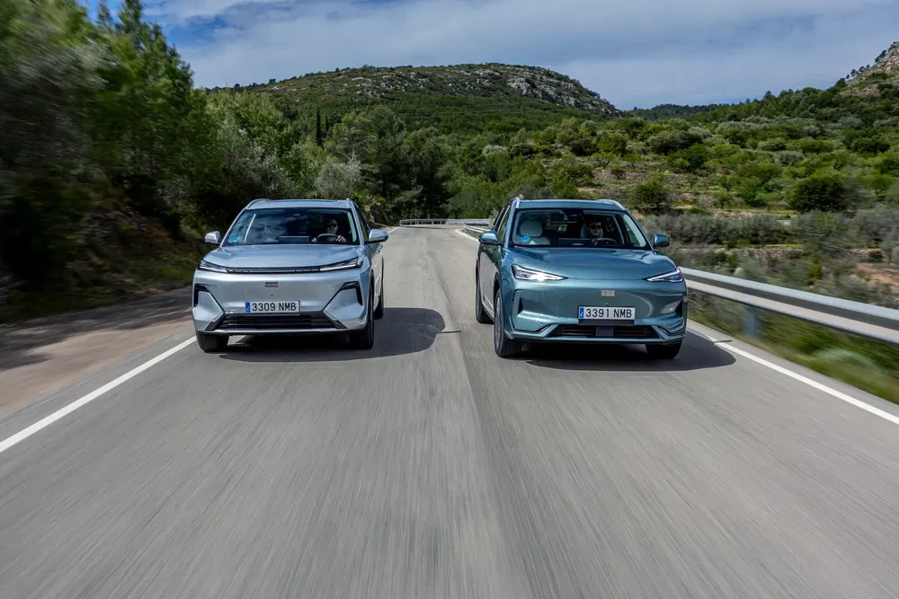Deux SUVs électriques Seat en mouvement sur route de campagne entre collines verdoyantes.