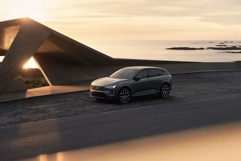 SUV électrique Genesis GV90 au bord de la mer au coucher du soleil spectaculaire.