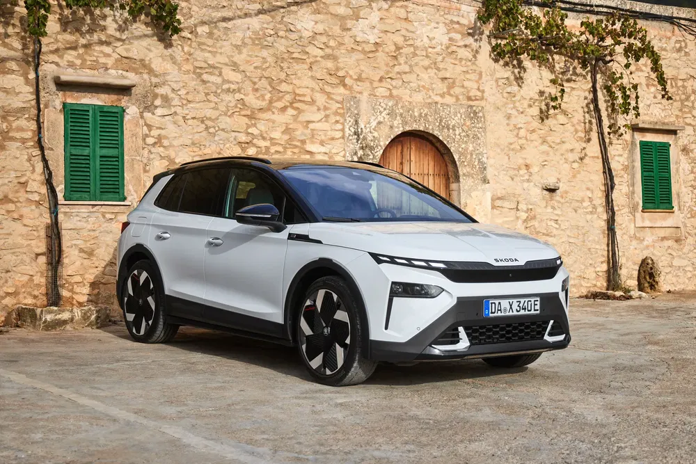 SUV Skoda moderne blanc stationné devant un bâtiment en pierre rustique.