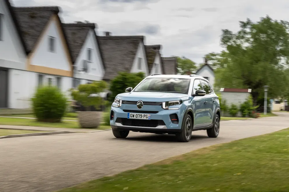 Un SUV Renault Captur bleu roulent dans un quartier résidentiel paisible.