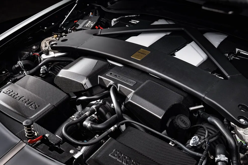 Moteur Brabus haute performance avec capot en fibre de carbone, barres de renfort visibles.