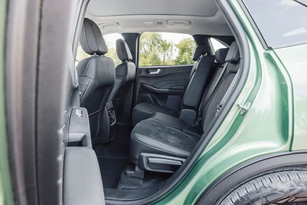 Intérieur spacieux de la banquette arrière d'une Ford Kuga verte en cuir noir.