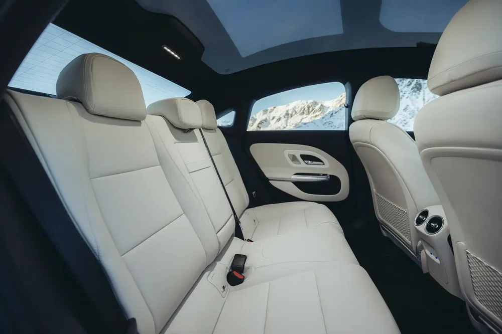 Luxueus auto-interieur met witte leren stoelen en uitzicht op besneeuwde bergen.