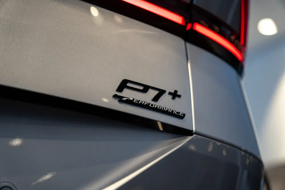 Close-up van een P7+ Performance badge op een grijze auto met opvallende LED achterlichten.