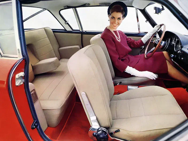 Intérieur d'une voiture vintage avec intérieur beige et détails élégants, femme au volant.
