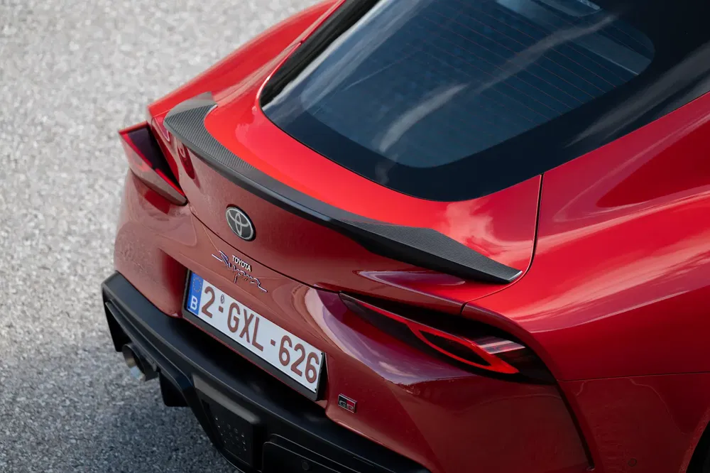 Achteraanzicht van rode Toyota Supra GR met spoiler en Belgische kentekenplaat.