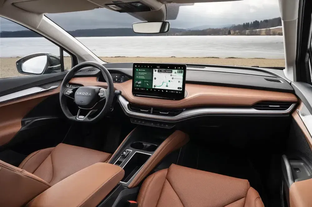 Interieur van Skoda met digitaal dashboard en bruine leren stoelen, uitzicht op meer.