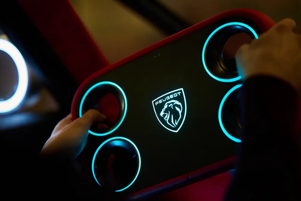Volant futuriste Peugeot avec logo lumineux et poignées circulaires rétroéclairées.
