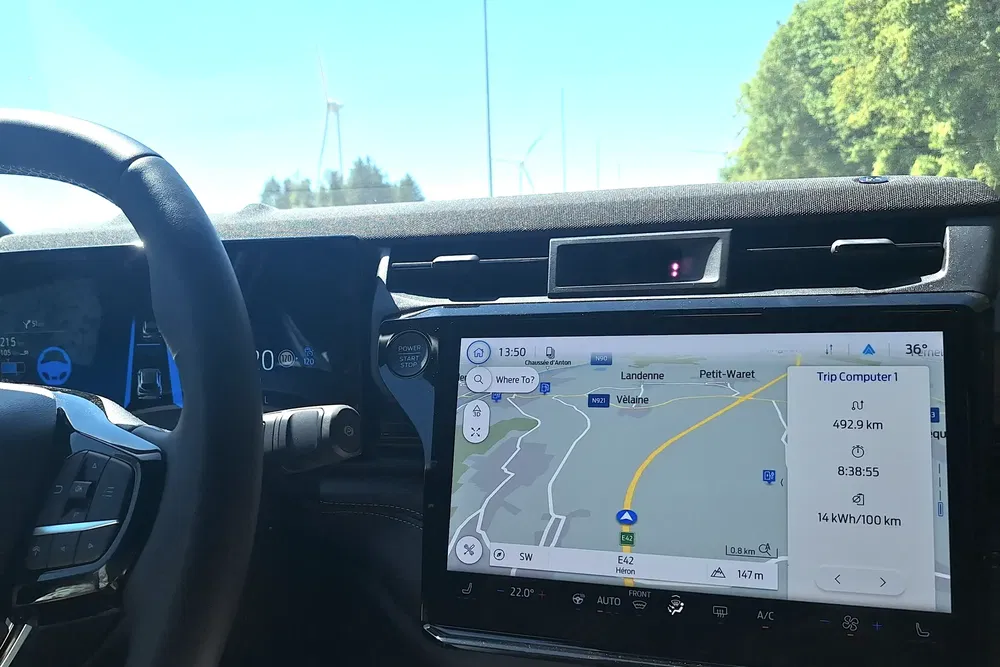 Tableau de bord moderne avec système de navigation, affichant un trajet en journée ensoleillée.