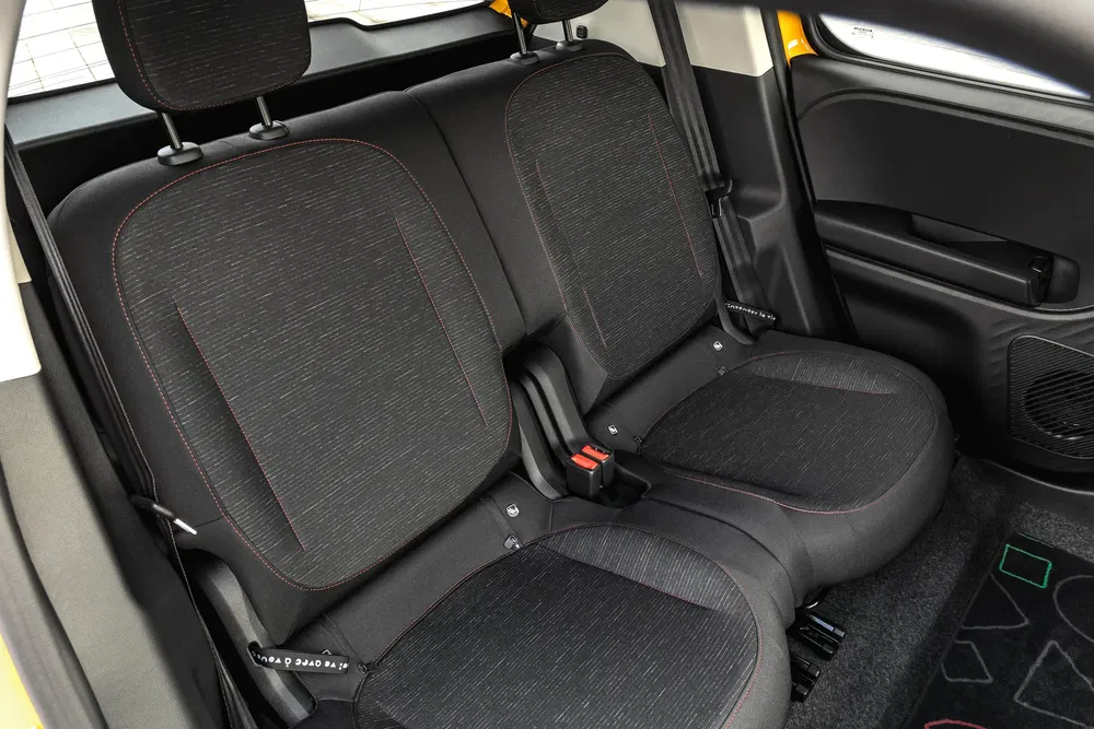 Intérieur arrière de la Volkswagen e-Up avec sièges en tissu noir et surpiqûres rouges.