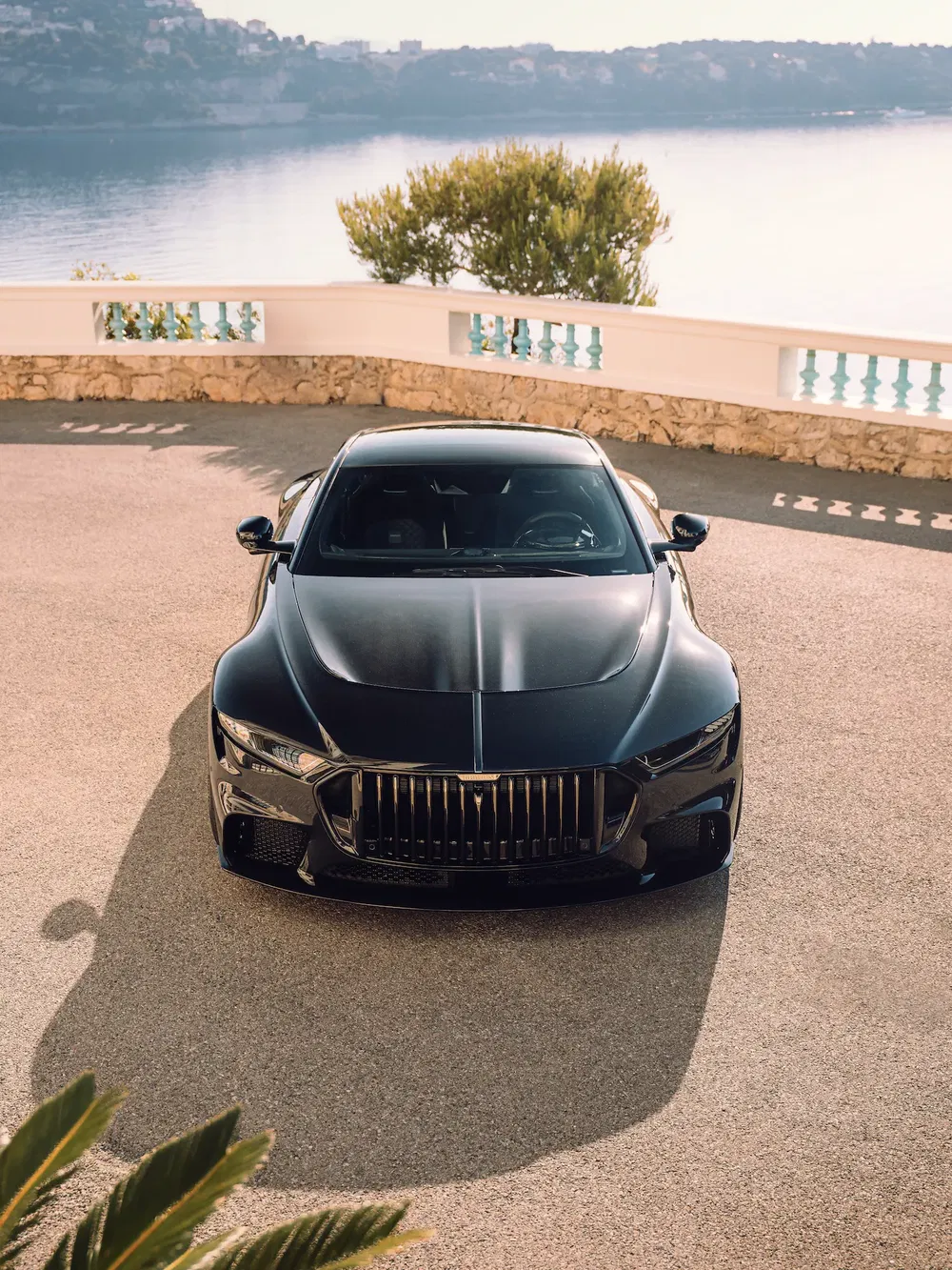 Voiture de luxe noire près de la mer avec paysage pittoresque, design élégant et moderne.