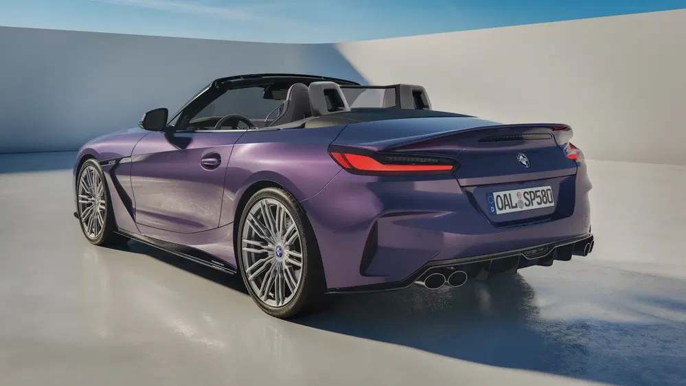 BMW Z4 cabriolet violet avec intérieur en cuir, stationné sur une surface réfléchissante.