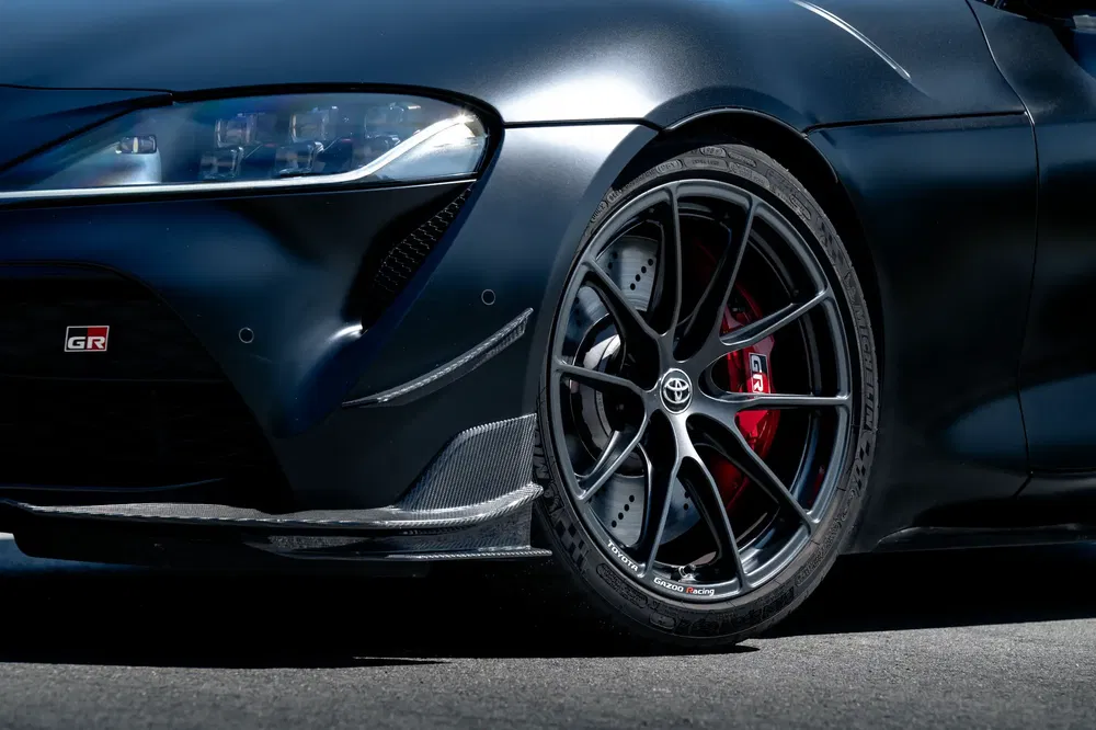 Zwarte Toyota GR Supra wiel, sportieve velgen en rode remklauwen op asfalt.