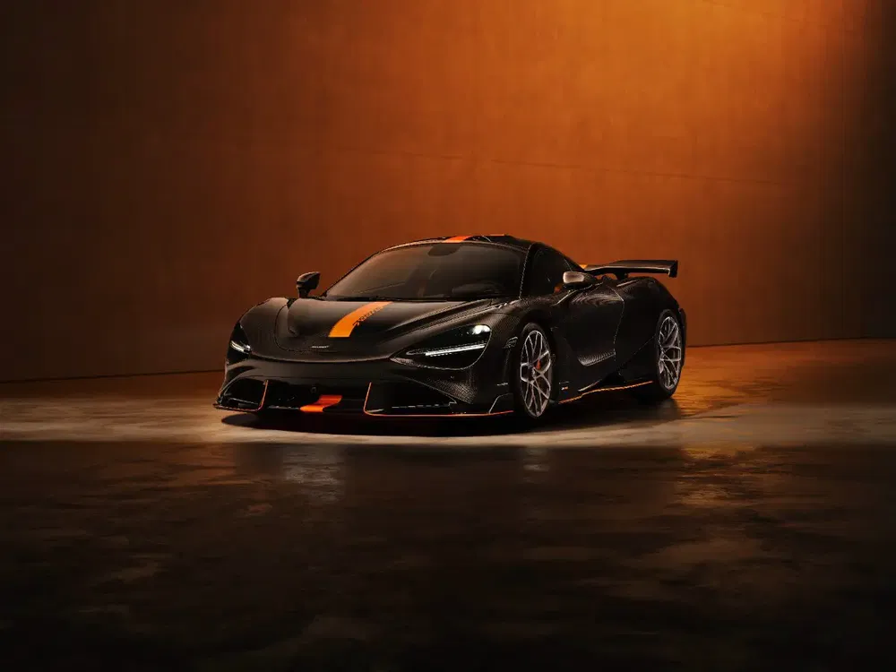 Supercar McLaren 720S met oranje streep, warme verlichting, donkere vloer en muur.