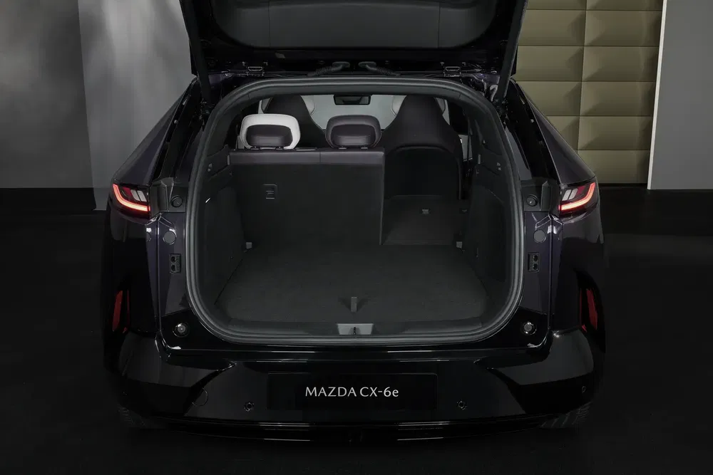 Coffre spacieux de la Mazda CX-6e, hayon ouvert, intérieur gris moderne.