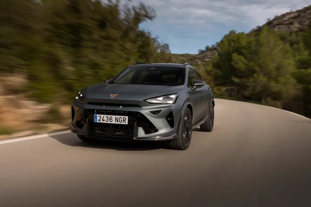 {"fr":"Cupra Tavascan roulant sur une route sinueuse bordée d'arbres en arrière-plan.","nl":"Cupra Tavascan rijdt op een bochtige weg met bomen op de achtergrond."}