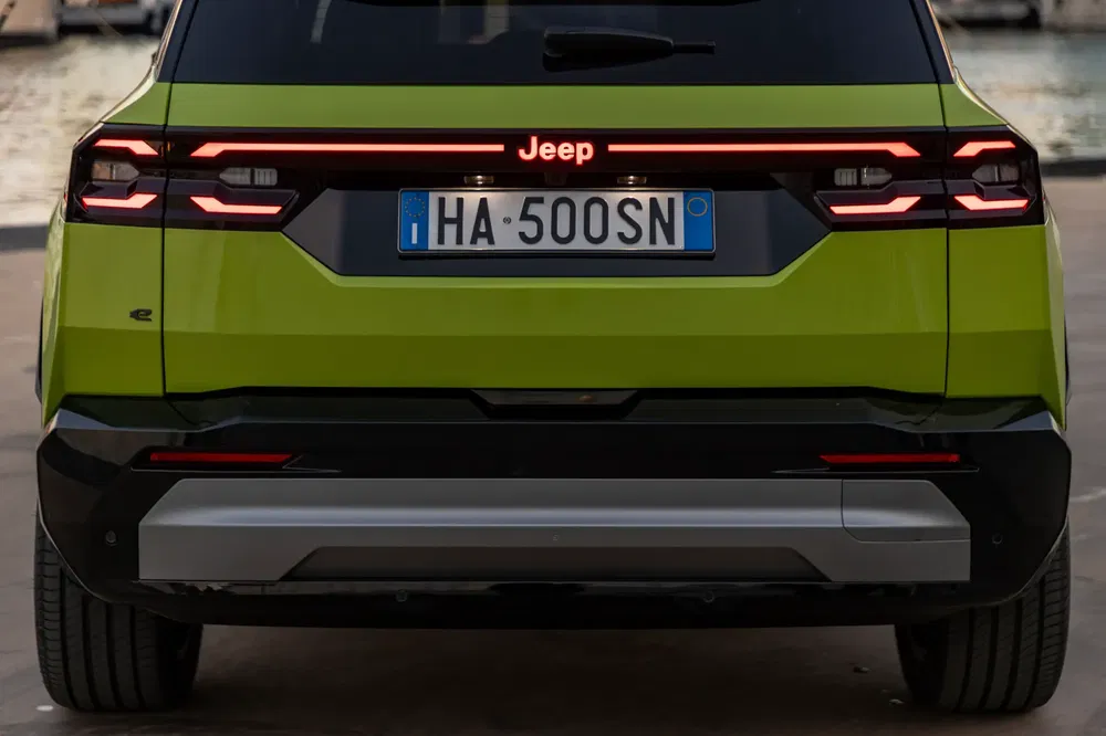 Achteraanzicht van groene Jeep met Europese plaat HA500SN bij water.