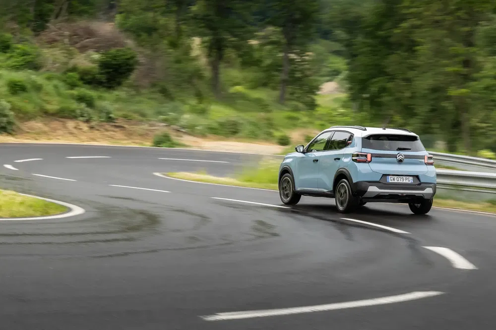 Citroën C3 Aircross sur route sinueuse en forêt, conduite dynamique.