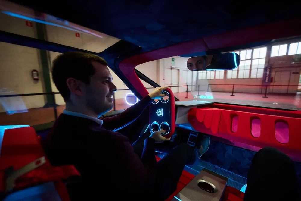 Conducteur souriant dans une voiture futuriste au design innovant avec intérieur rouge.