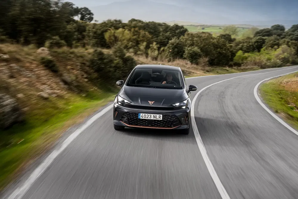 Cupra Born électrique sur route sinueuse au milieu de la campagne verdoyante.