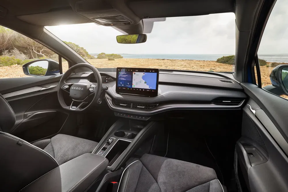 Intérieur moderne de la Škoda Enyaq avec écran tactile, vue sur la mer en arrière-plan.