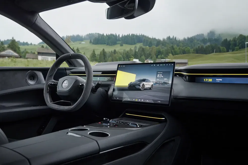 Intérieur moderne de voiture électrique Lotus avec écran tactile, volant et paysages verdoyants.