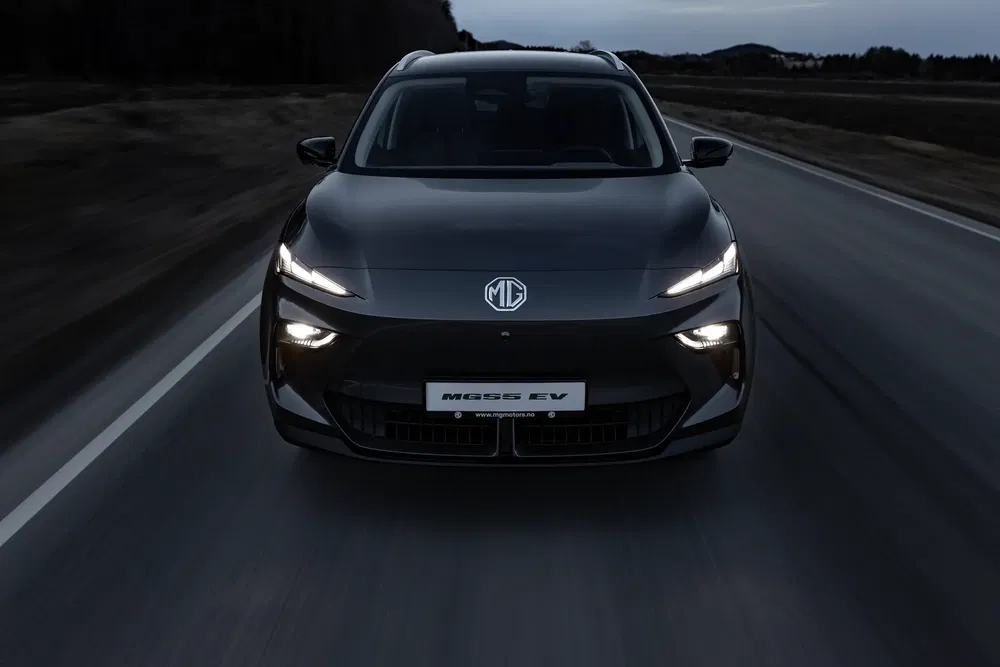 MG5 EV roulant sur une route sombre, phares allumés, ambiance nocturne élégante.