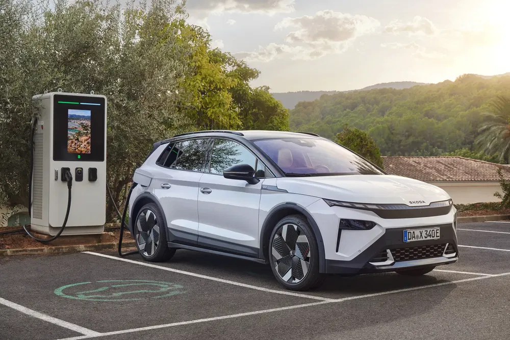 Nouveau SUV électrique Škoda en charge, paysage rural, station de recharge moderne.
