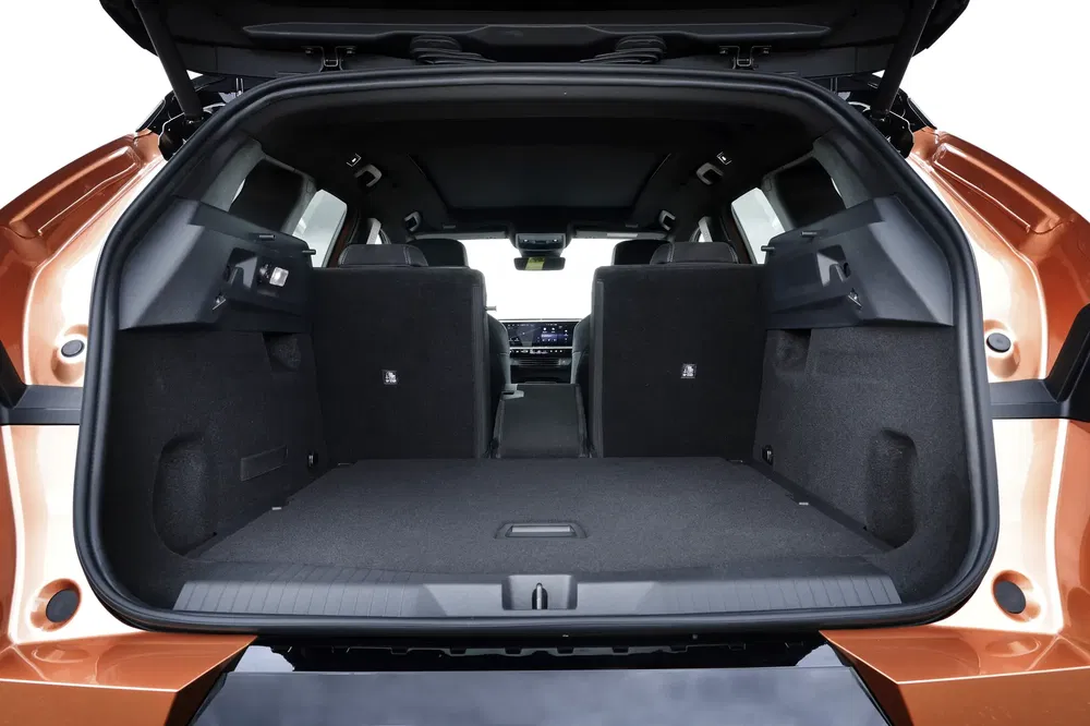 Espace de chargement d'un SUV moderne Nissan avec banquettes arrière rabattables, couleur bronze.
