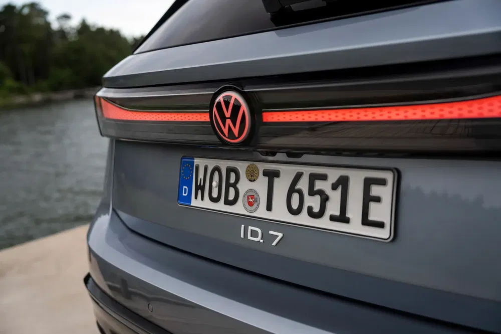 Arrière de la Volkswagen ID.7 à côté d'un lac, montrant le logo et la plaque allemande.