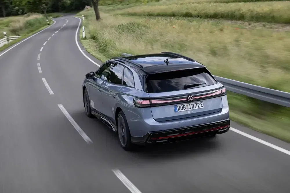 Vue arrière de la Volkswagen ID.7 GTX sur route de campagne sinueuse.