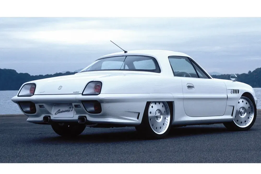 Mazda Cosmo Sport blanche au bord de l'eau, style rétro emblématique des années 60.