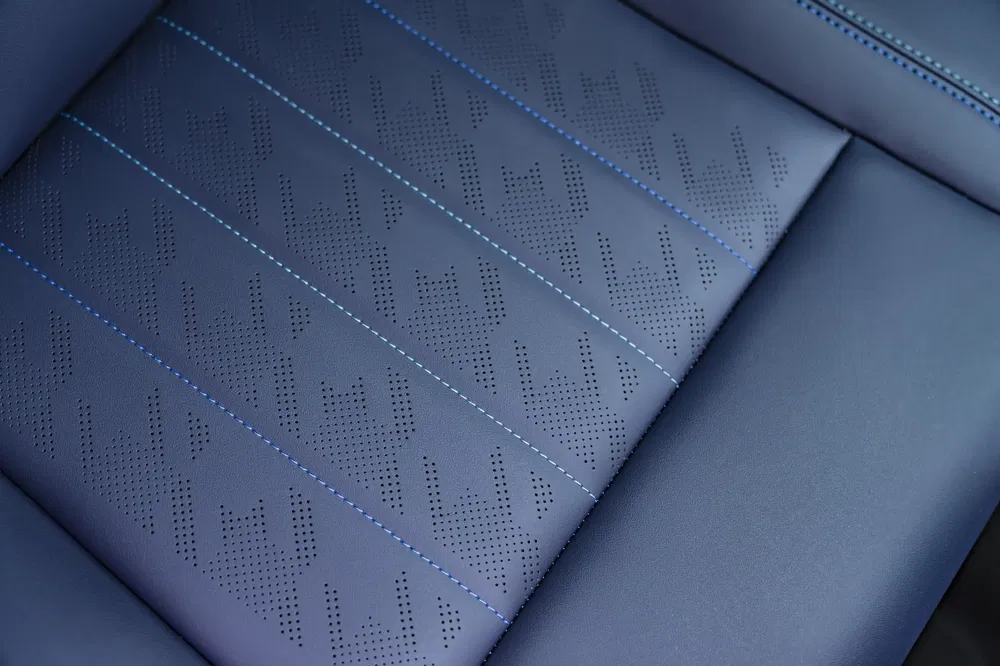 Sellerie de voiture en cuir bleu avec motifs perforés et surpiqûres bleues.