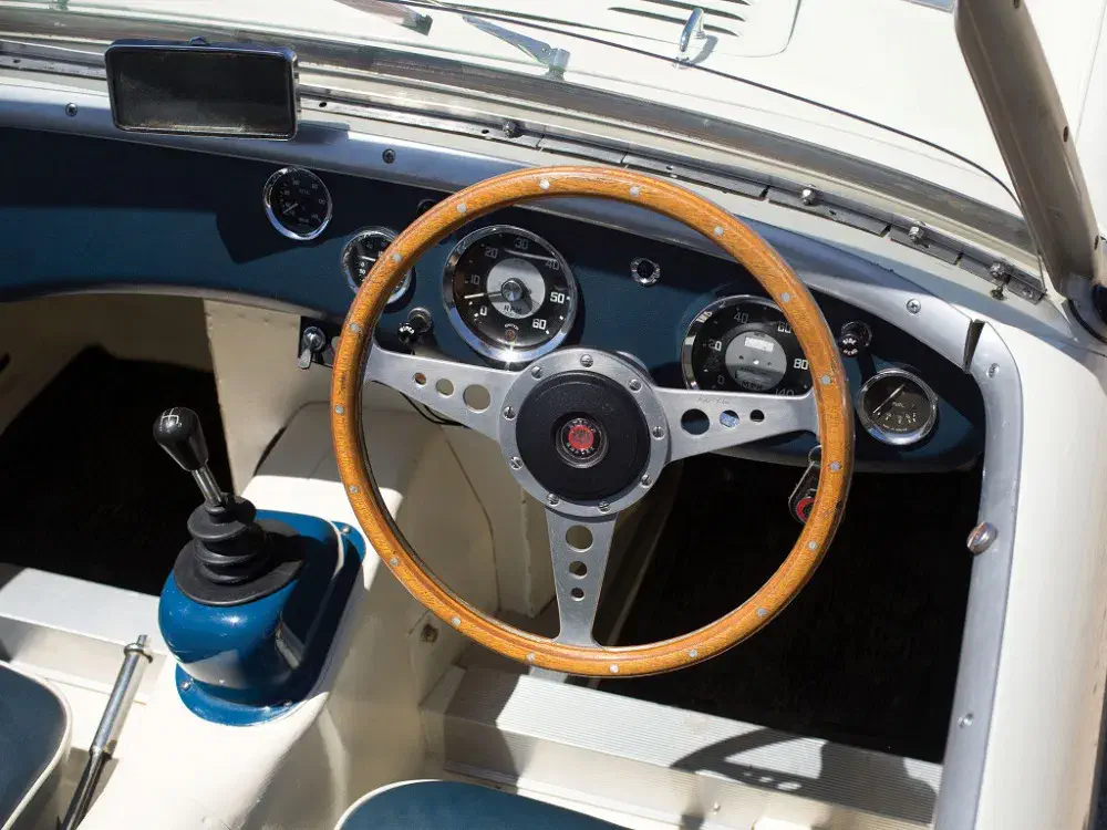 Tableau de bord rétro d'une voiture classique avec volant en bois et compteur vintage.