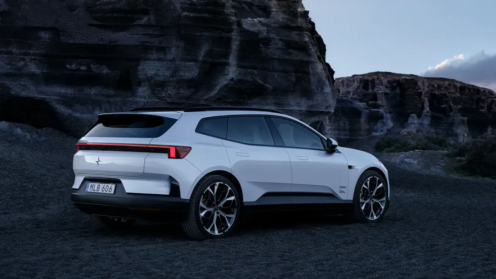 Polestar 3 blanche garée devant une formation rocheuse imposante au crépuscule.