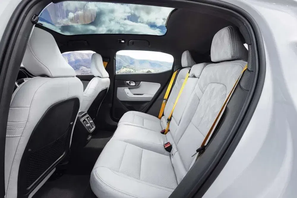 Intérieur luxueux d'une voiture avec sièges arrière en cuir blanc et toit panoramique.