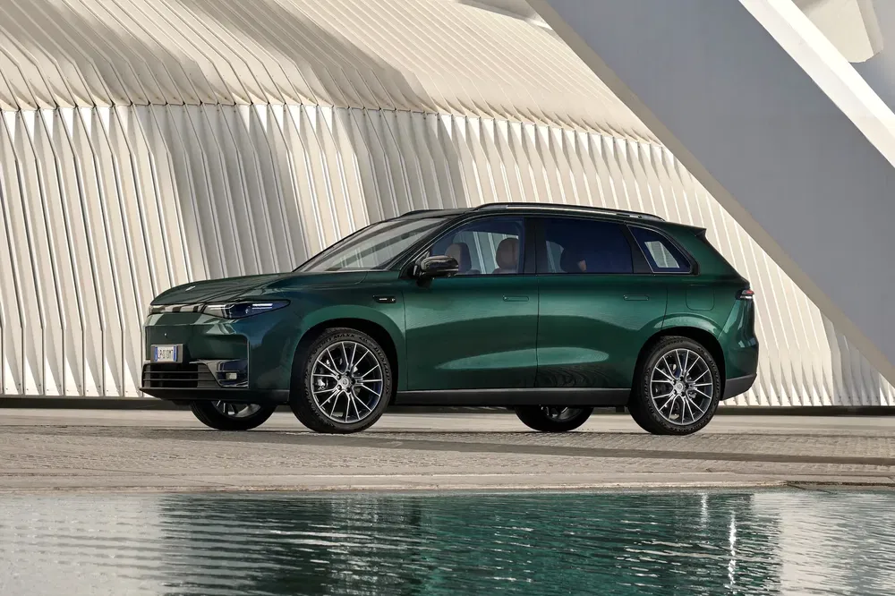 Groene Aiways U6 SUV voor moderne architectuur met weerspiegeling in water.