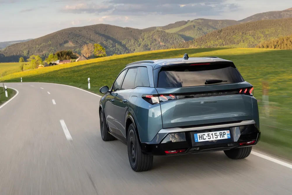 Peugeot 3008 roulant sur une route de campagne, montagnes en arrière-plan.