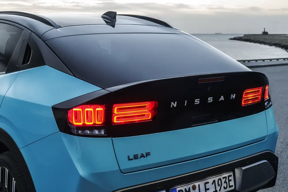 Achteraanzicht van de Nissan Leaf met brandende achterlichten aan de waterkant.