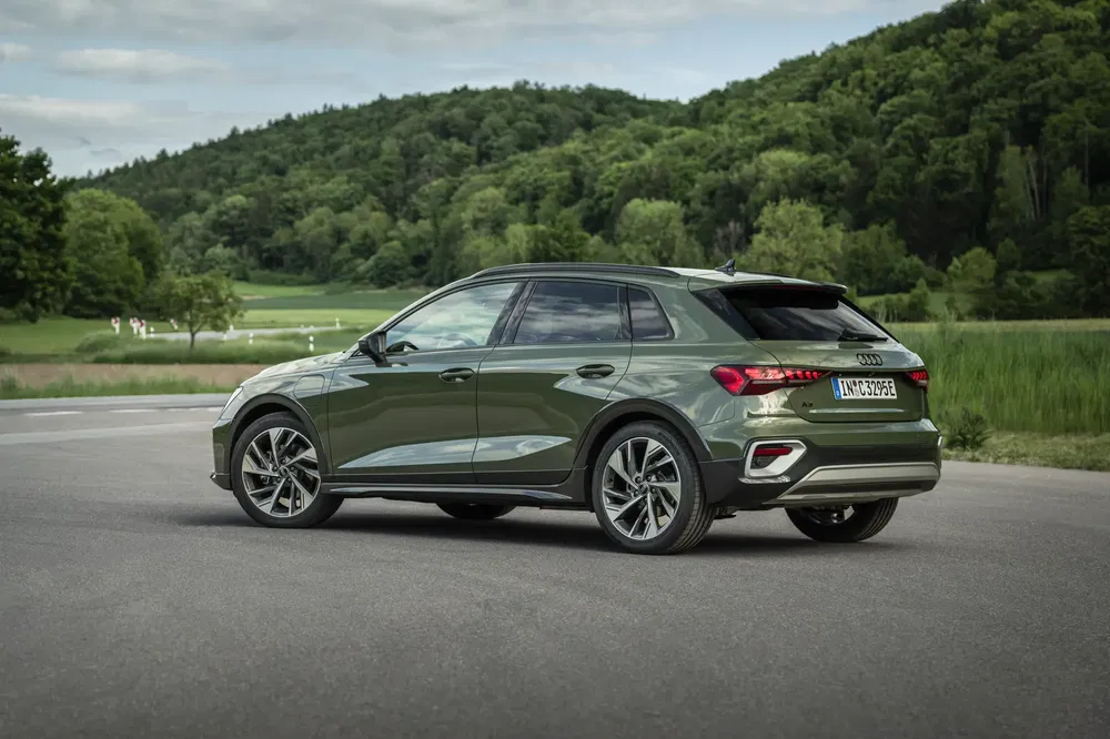 Audi Q5 vert sur route avec arrière-plan de forêt verdoyante.