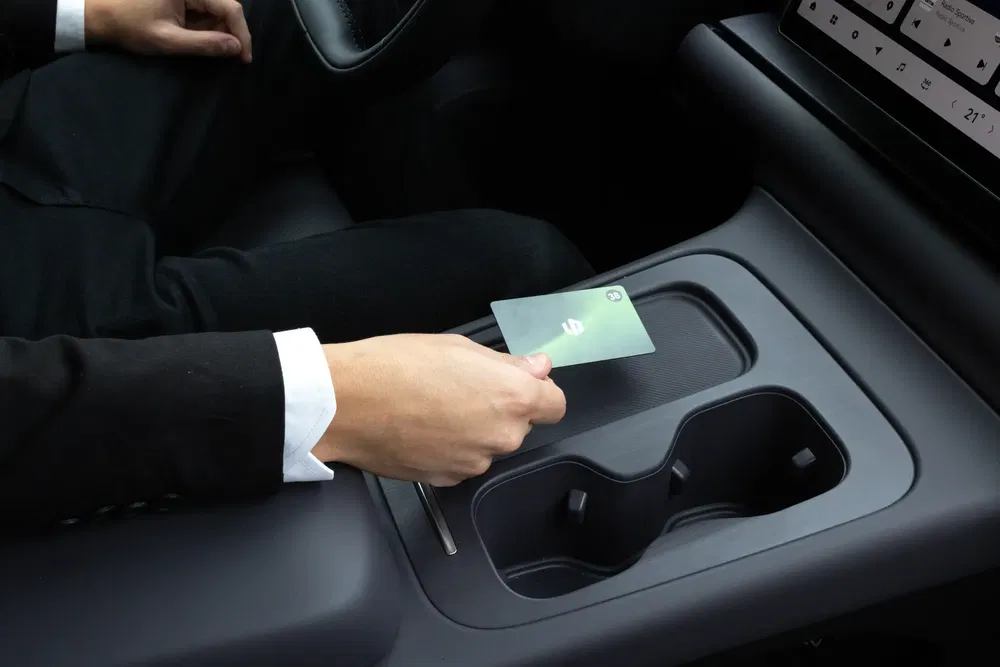 Conducteur tenant une carte dans une voiture avec écran tactile et porte-gobelets modernes.