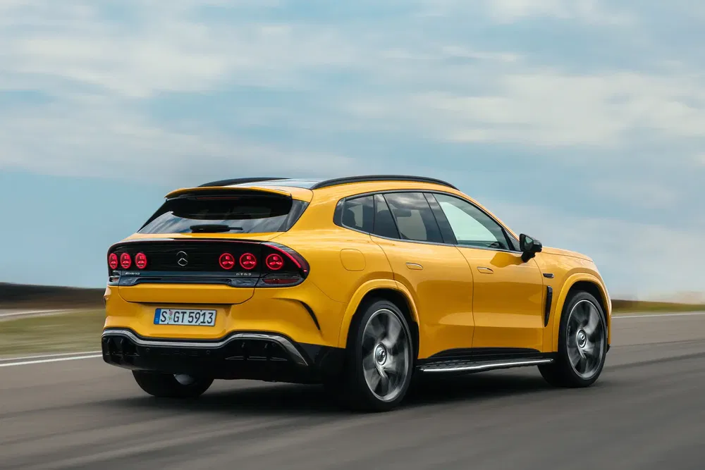 Gele sportieve Mercedes-Benz SUV met zwarte velgen op snelle weg, achteraanzicht.