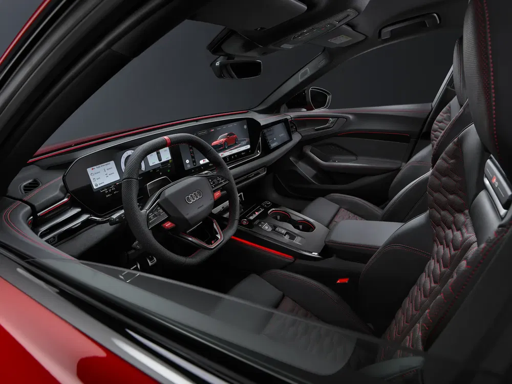 Luxueus Audi-interieur met sportstuur en zwarte lederen stoelen met rode stiksels.
