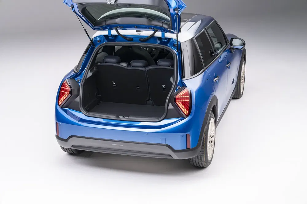 Mini Cooper Countryman bleu avec coffre ouvert montrant espace de chargement robuste.