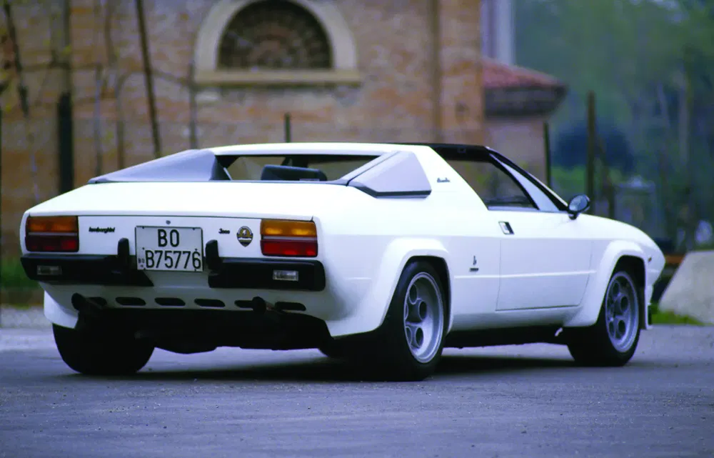 L'arrière d'une Lamborghini Jalpa blanche, garée devant un bâtiment en brique.