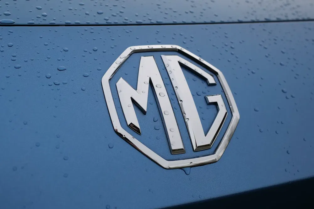 Logo MG sur une carrosserie bleue mouillée de gouttes de pluie.