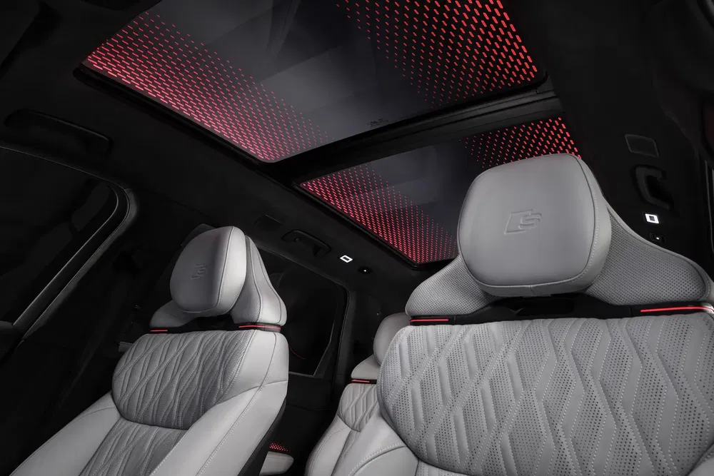 Intérieur de luxe Audi avec sièges en cuir et toit panoramique lumineux rouge.