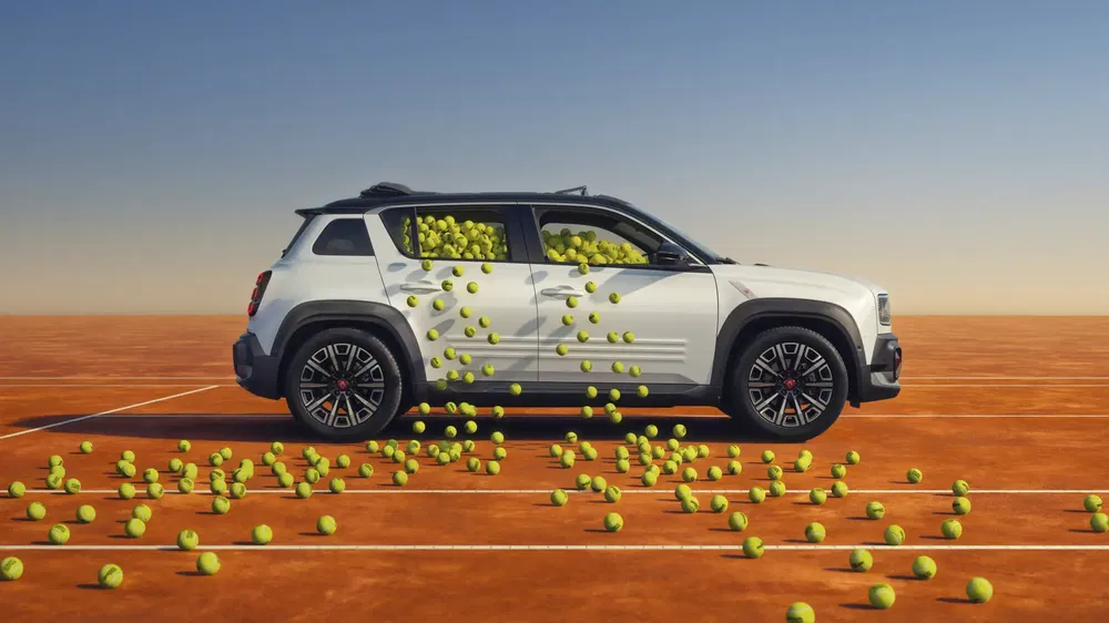 Jeep Renegade blanc rempli de balles de tennis sur un court au sol orange.