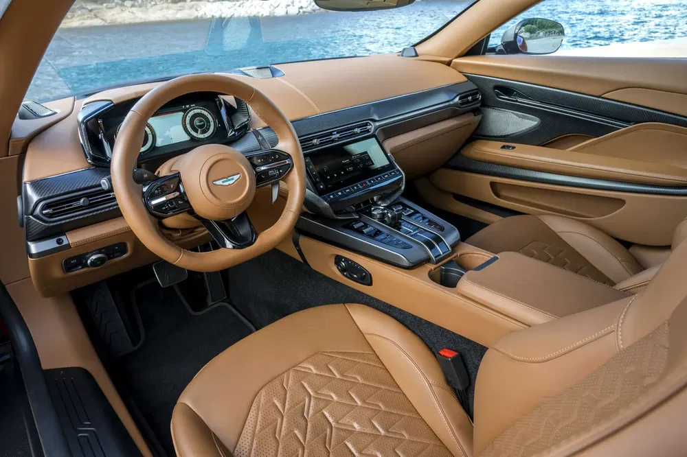 Intérieur luxueux de l'Aston Martin DB12 avec finitions en cuir beige et technologie avancée.