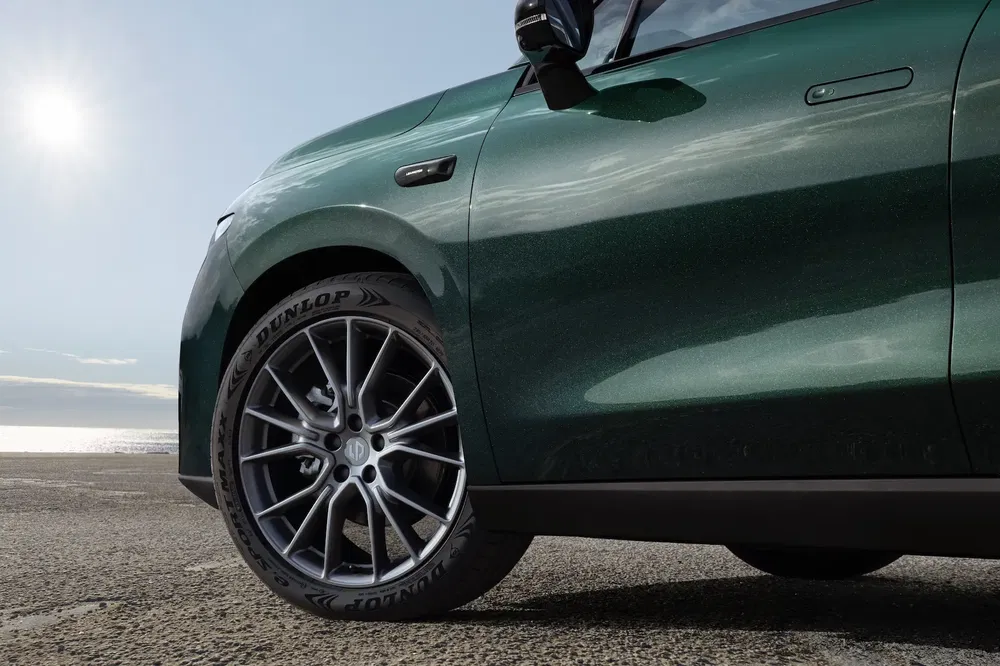 Close-up van Dunlop-band op groene auto met uitzicht op oceaan op achtergrond.